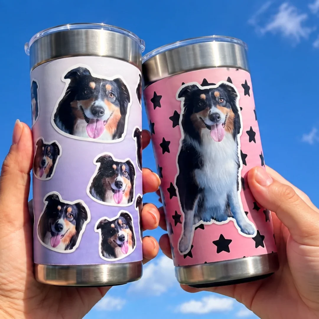 Two personalized Otto tumblers held against a blue sky.